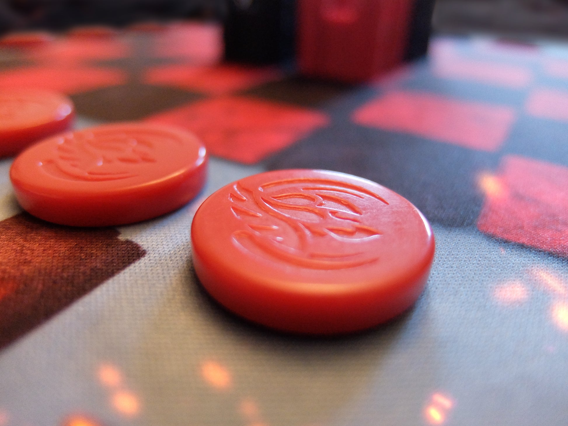 Close-up of red game pieces on a checkered kopis board